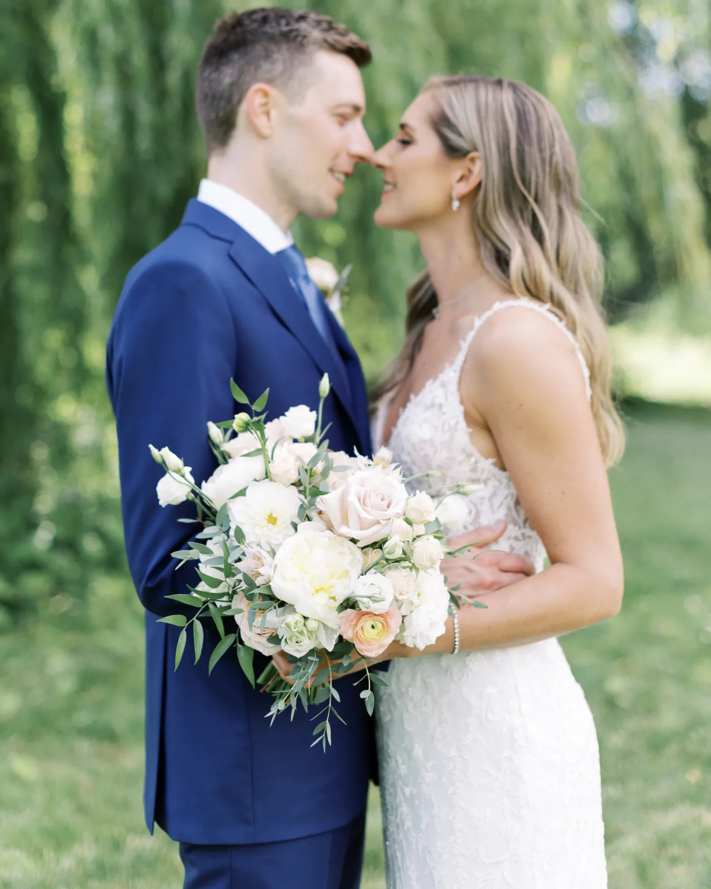 Couple holding a soft white and blush wedding bouquet